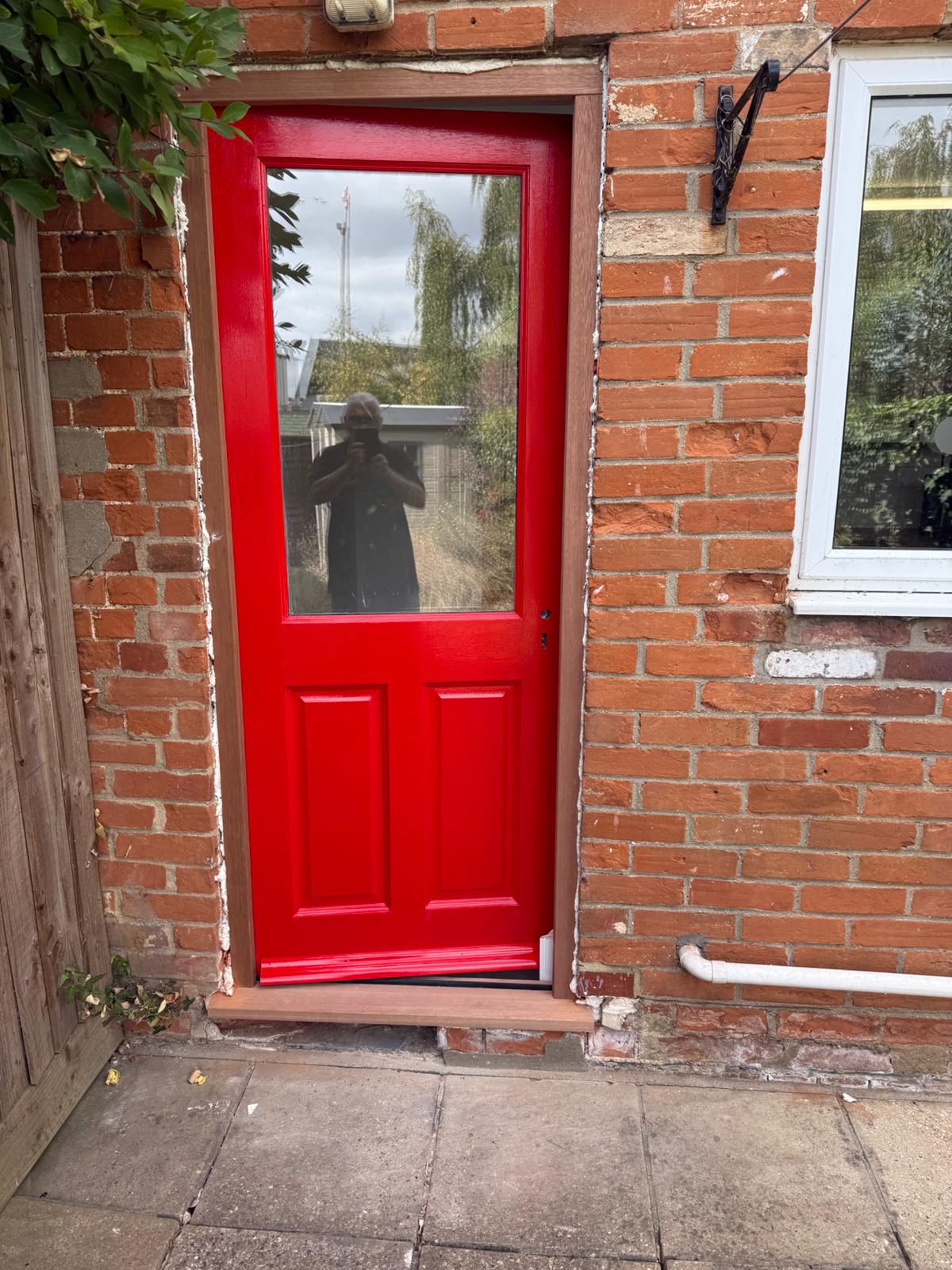 Red painted external door installation in Suffolk